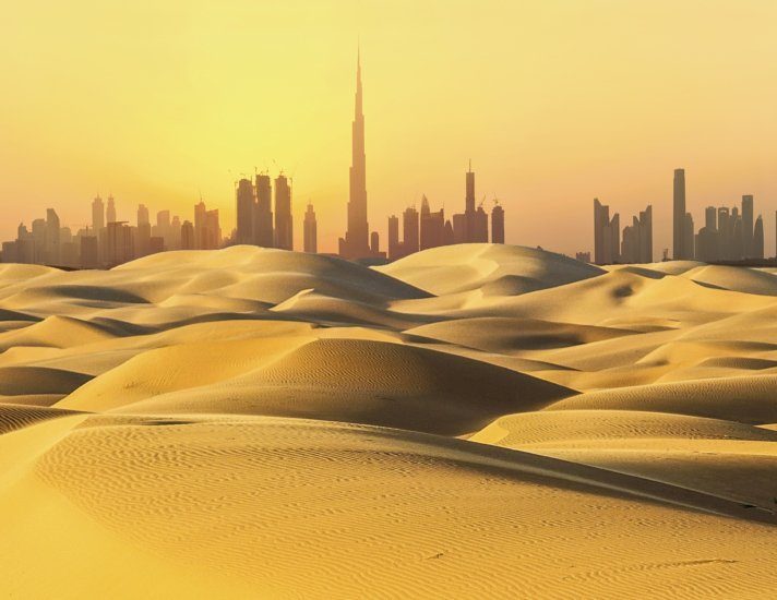 Dubai skyline in desert at sunset.