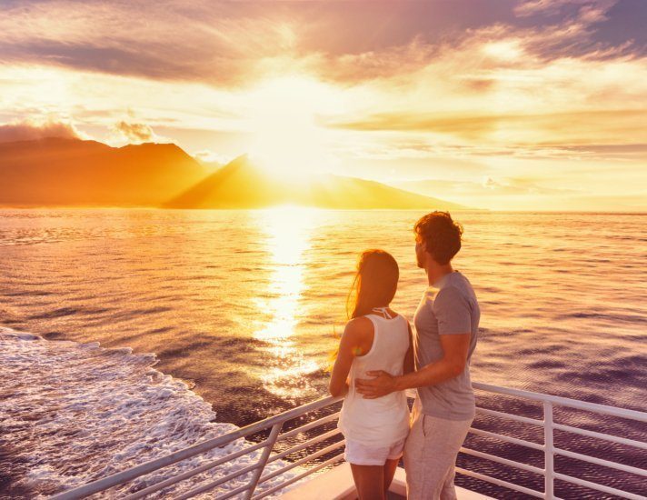 Travel cruise ship couple on sunset cruise in Hawaii holiday. Two tourists lovers on honeymoon travel enjoying summer vacation.